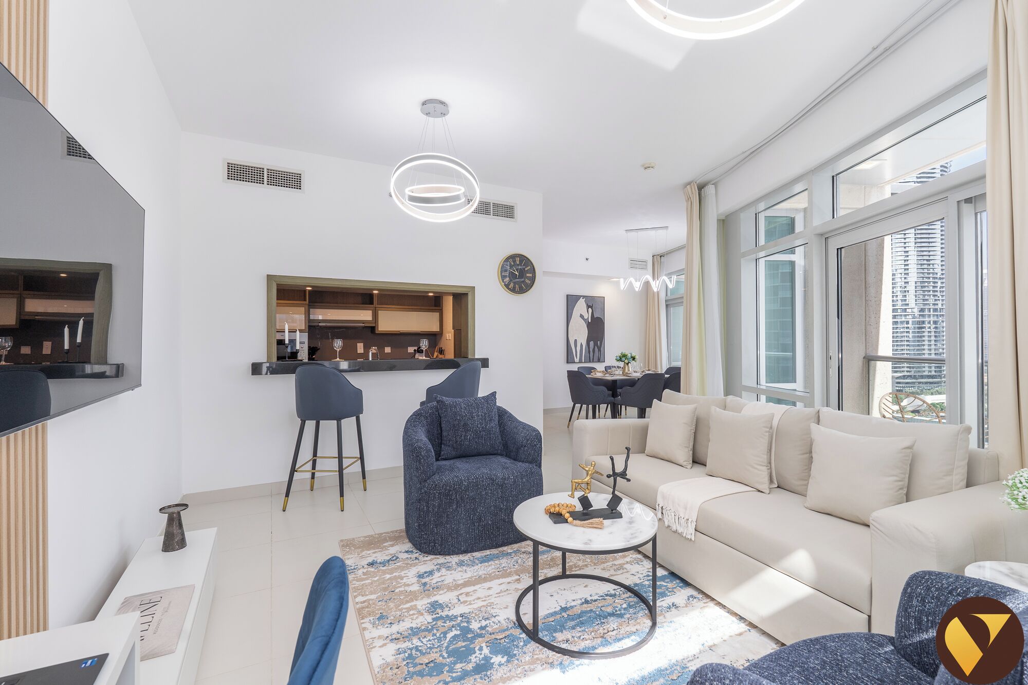 A modern living room with a sofa, chairs, a coffee table, and a dining area with a kitchen in the background.