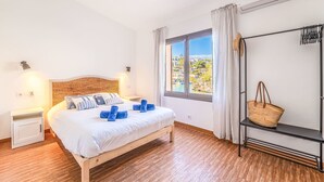 Ein Schlafzimmer mit Bett, Fenster mit Aussicht, Deckenventilator und Nachttisch.