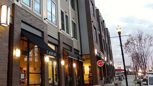 A row of buildings with storefronts, including one with a sign that reads "CADEAU".