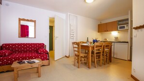 A compact living space with a red sofa, wooden dining table, and a kitchenette. - Holiday home for 6 people with balcony (Val Cenis)
