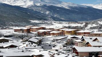 A snow-covered town with buildings, including a hotel with multiple floors and a ski lift visible in the background.