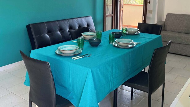 A dining area with a teal tablecloth, black chairs, and a white pedestal table.