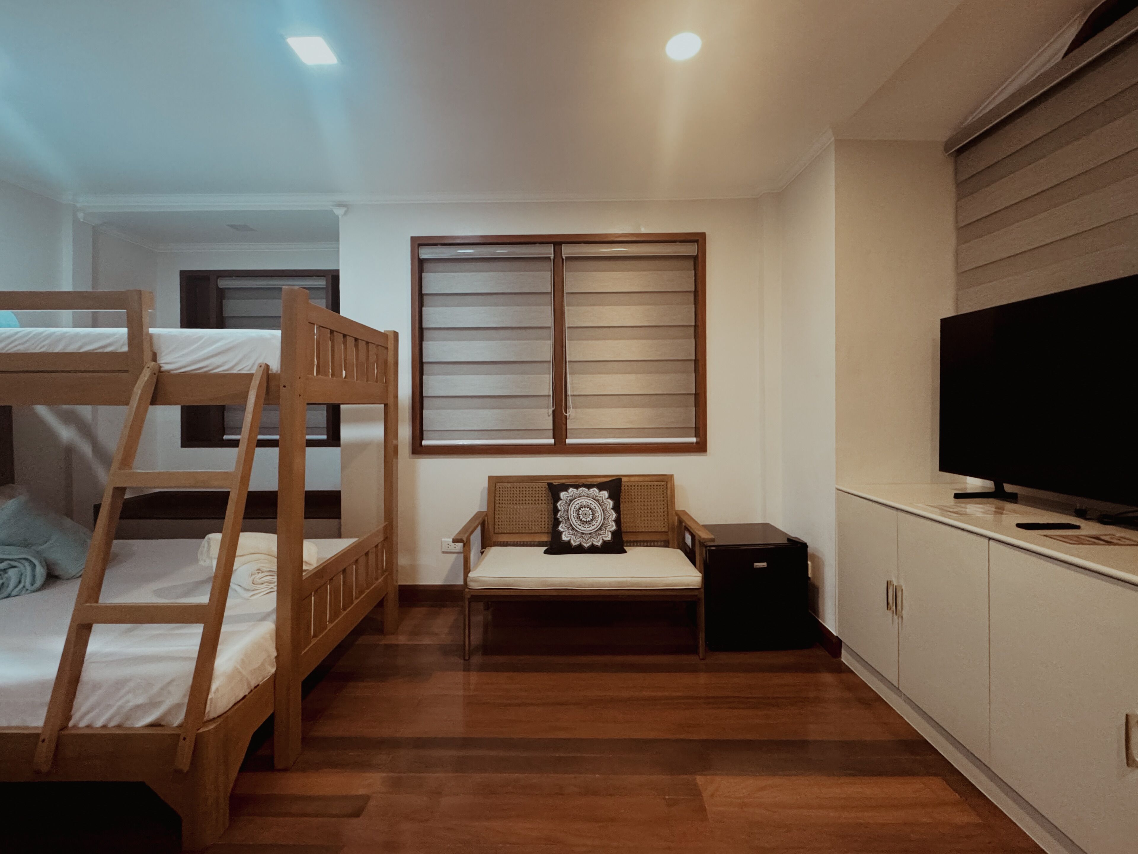 Una habitación con literas, televisión y ventana con persianas.