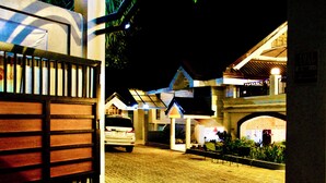 A paved driveway leading to a building with a gated entrance, a parked car, and a sign indicating a full stop. - Hidden Oasis Resort (Gingoog)