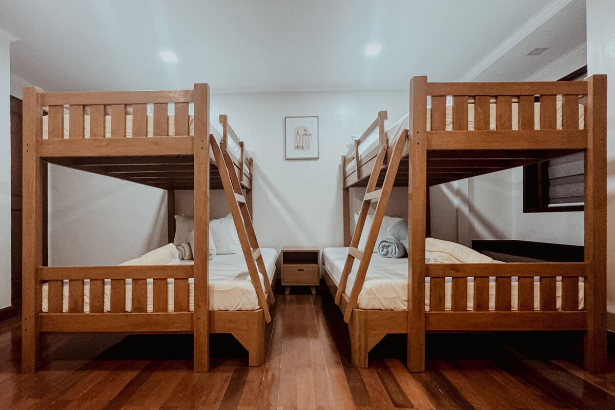 A room with two bunk beds, a small bedside table, and a wall-mounted picture.