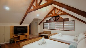 A bedroom with two beds, a TV, and wooden beams. - Hidden Oasis Resort (Gingoog)