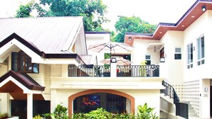 A two-story building with a balcony, a covered patio, and a decorative archway. - Hidden Oasis Resort (Gingoog)