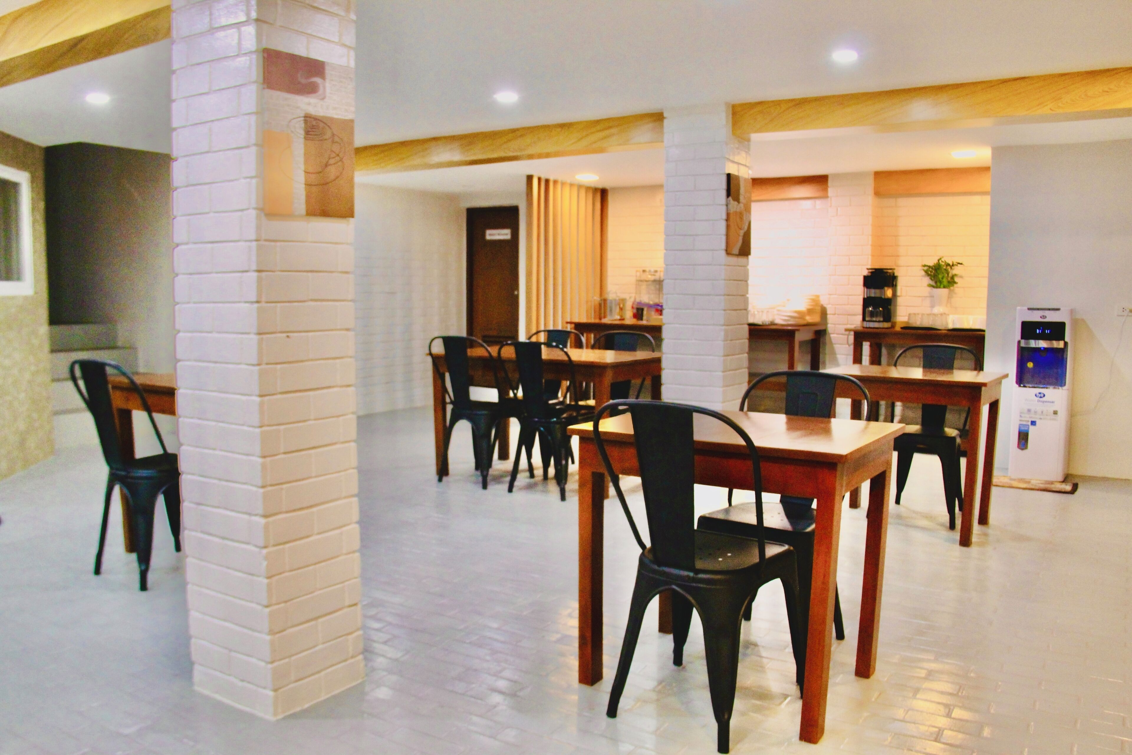 A dining area with multiple tables and chairs, a coffee machine, and a refrigerator.