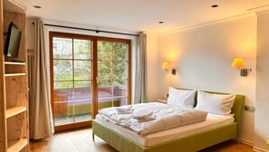 A bedroom with a bed, a TV on a shelf, a sliding glass door, and two wall-mounted lamps.