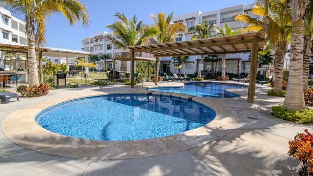 A pool area with two circular pools, palm trees, and a covered seating area.