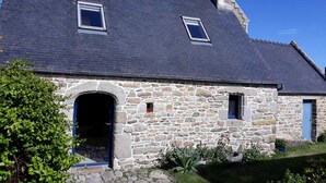 A stone house with a dark slate roof, two small windows, and a blue door. - Quiet house with private garden close to the sea (Roscoff)