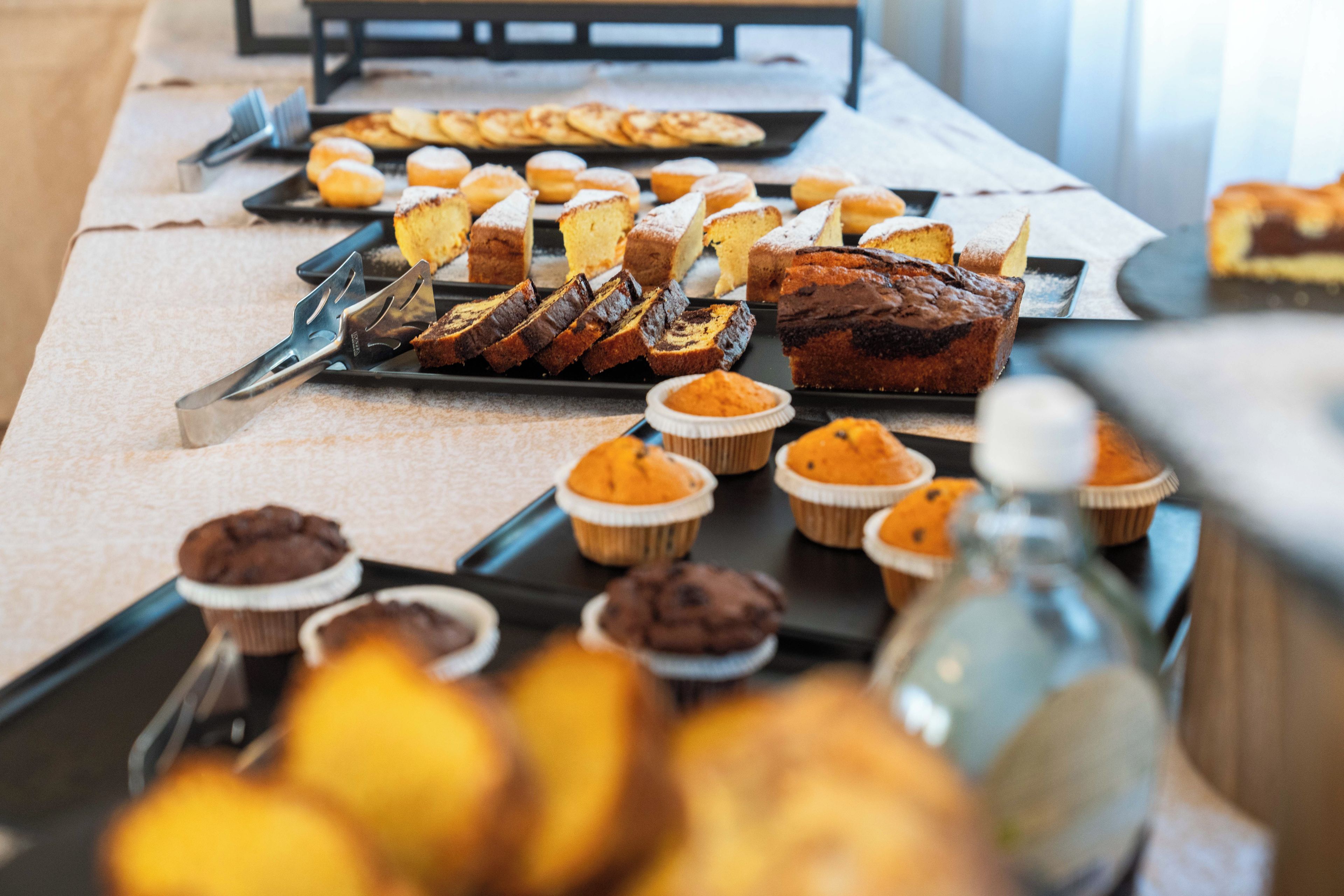A buffet table with various baked goods including muffins, cakes, and pastries.