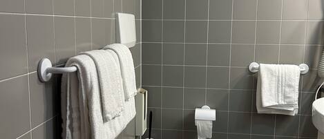A modern bathroom with grey tiles, a white toilet, a bidet, and a sink.