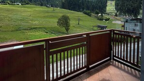 Uma varanda com vista para um campo verde e colinas arborizadas.