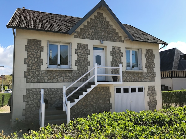 A two-story house with a stone facade, a white front door, and a small balcony. - Vacation villa located 50 meters from the ocean. (Blonville-sur-Mer)