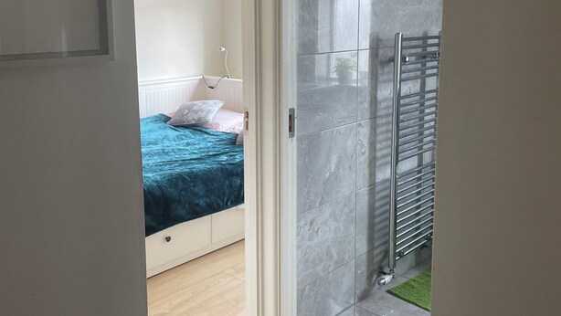 Une salle de bain moderne avec une douche à parois de verre, un porte-serviettes et un tapis vert.