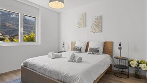A modern bedroom with a large bed, a hanging light fixture, and two wall-mounted artworks. - New apartment between plain and mountains (Saxon)