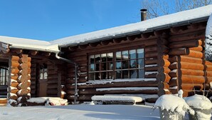 A log cabin with a snow-covered roof and windows, surrounded by snow. - Fjordhygge (Jægerspris)