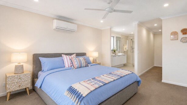 Quarto com cama, mesas de cabeceira, ventilador de teto, ar condicionado e banheiro ao fundo.