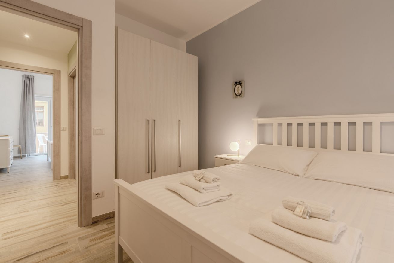 Een slaapkamer met een bed, nachtkastje met een lamp en een kledingkast.