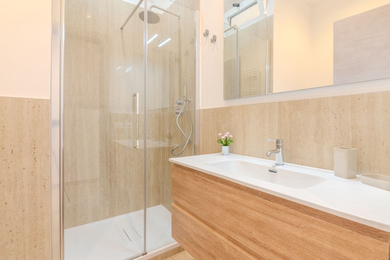 A modern bathroom with a glass-enclosed shower, a wooden vanity, and a large mirror.