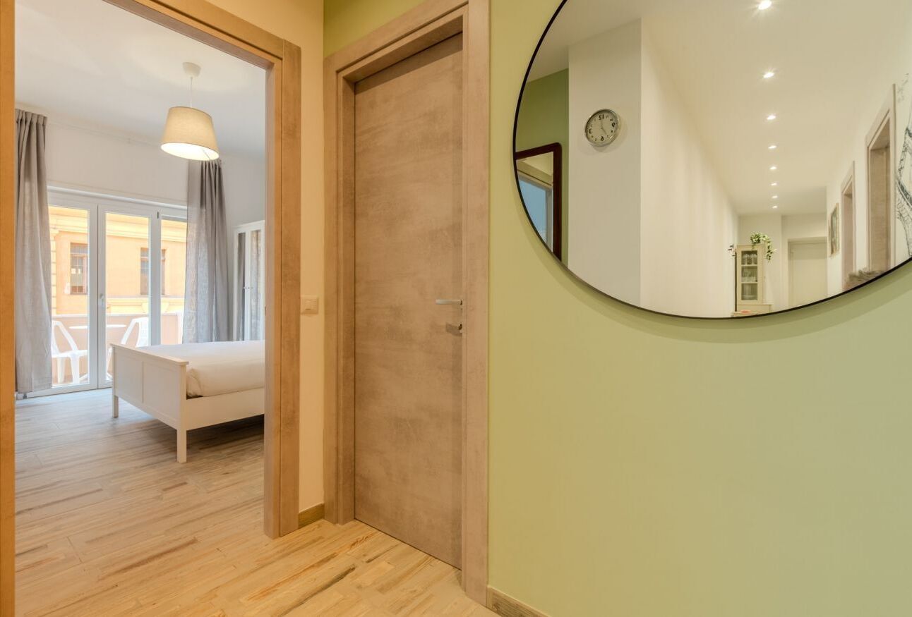 Une chambre à coucher avec un lit, une porte en bois et un miroir rond accroché au mur.
