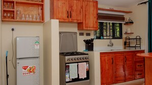 Une cuisine avec des meubles de rangement en bois, un réfrigérateur, un four et une fenêtre donnant sur les arbres.