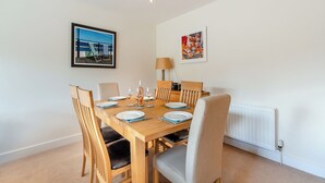 Un comedor con una mesa de madera, sillas y un cuadro enmarcado con una playa.