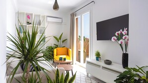 A modern living room with a sofa, yellow armchair, and potted plants.