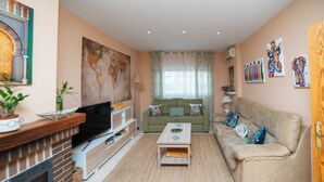 Een woonkamer met een open haard, bank, salontafel en decoratieve kussens.