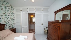 Een slaapkamer met een bed, een dressoir en een kledingkast.