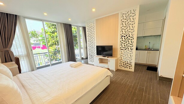 Een moderne hotelkamer met een groot bed, een televisie en een balkon met gordijnen.