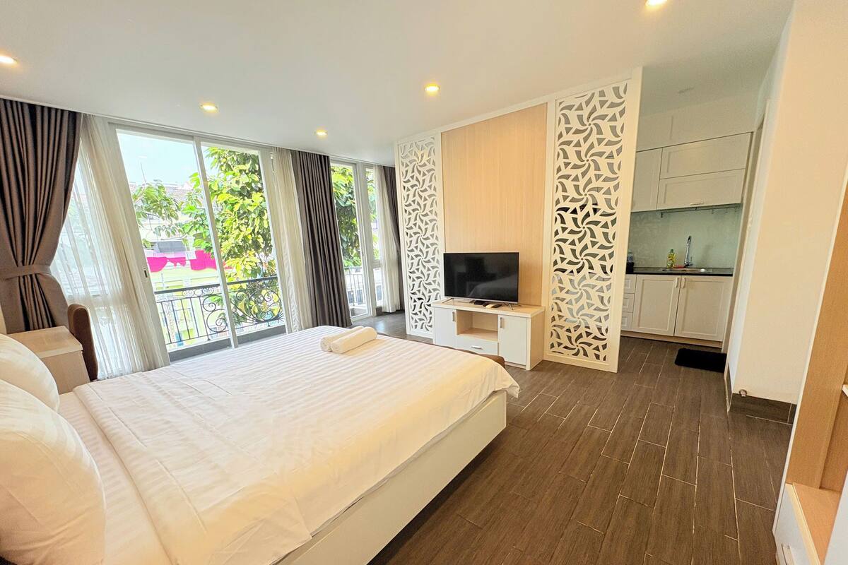 Een moderne hotelkamer met een groot bed, een televisie en een balkon met gordijnen.