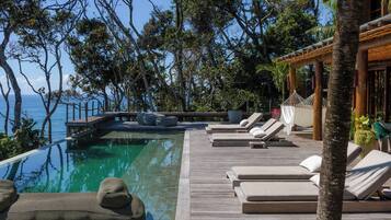 Una piscina al aire libre, sillones reclinables de piscina