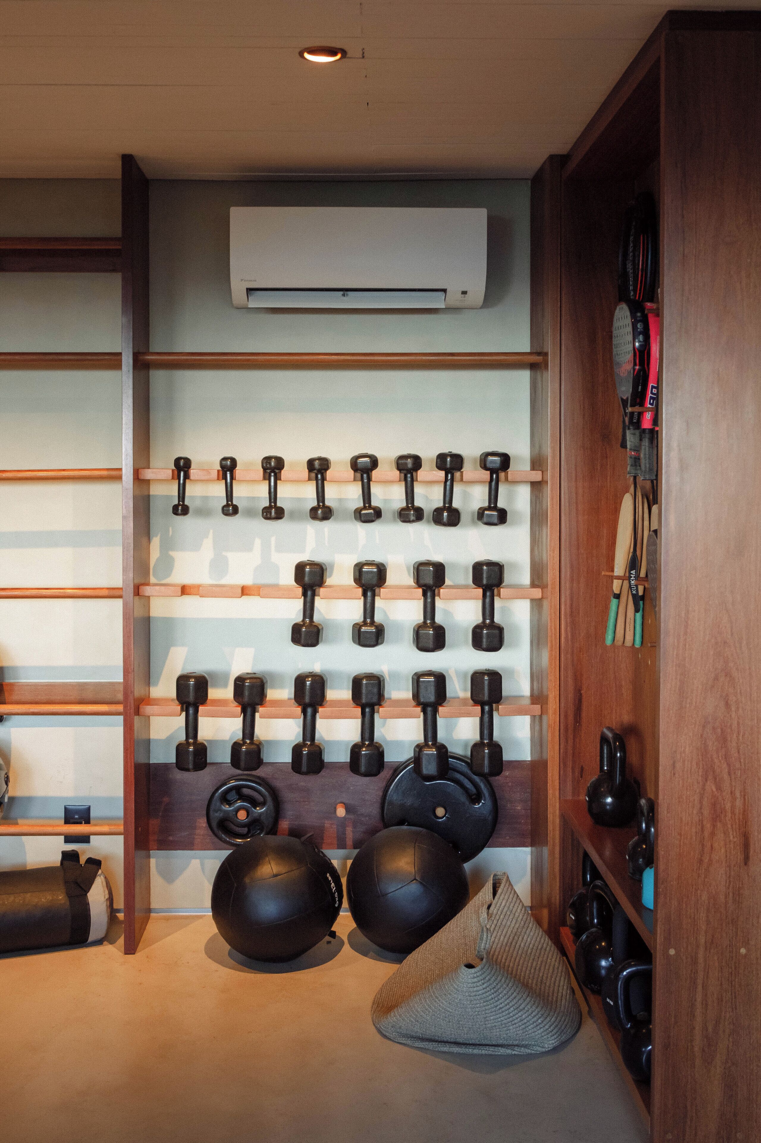 A gym with various exercise equipment, including dumbbells, kettlebells, and a yoga mat.
