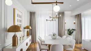 A modern dining area with a white table, beige chairs, and a chandelier. - 4bd Ensuite Luxury Residence Kolonaki, Apartment (Athens)