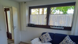 Una sala de estar con un sofá azul, una mesa de centro de madera y una ventana con cortinas.