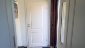 Un pasillo con una puerta blanca, un tapete oscuro y piso de madera.