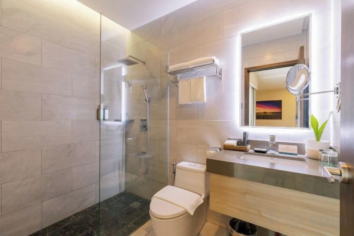 Un baño moderno con ducha envuelta en vidrio, inodoro, tocador con espejo y un perchero para toallas.