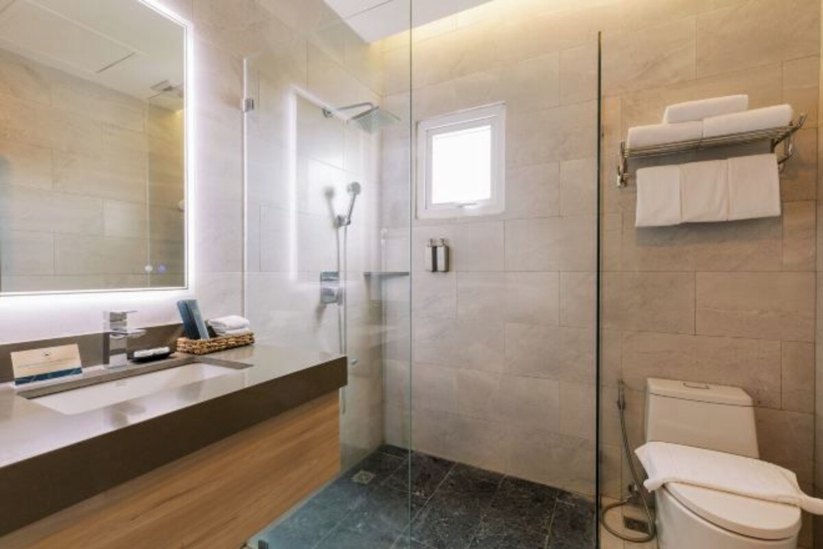 Un baño moderno con cabina de ducha de vidrio, inodoro y tocador con espejo.