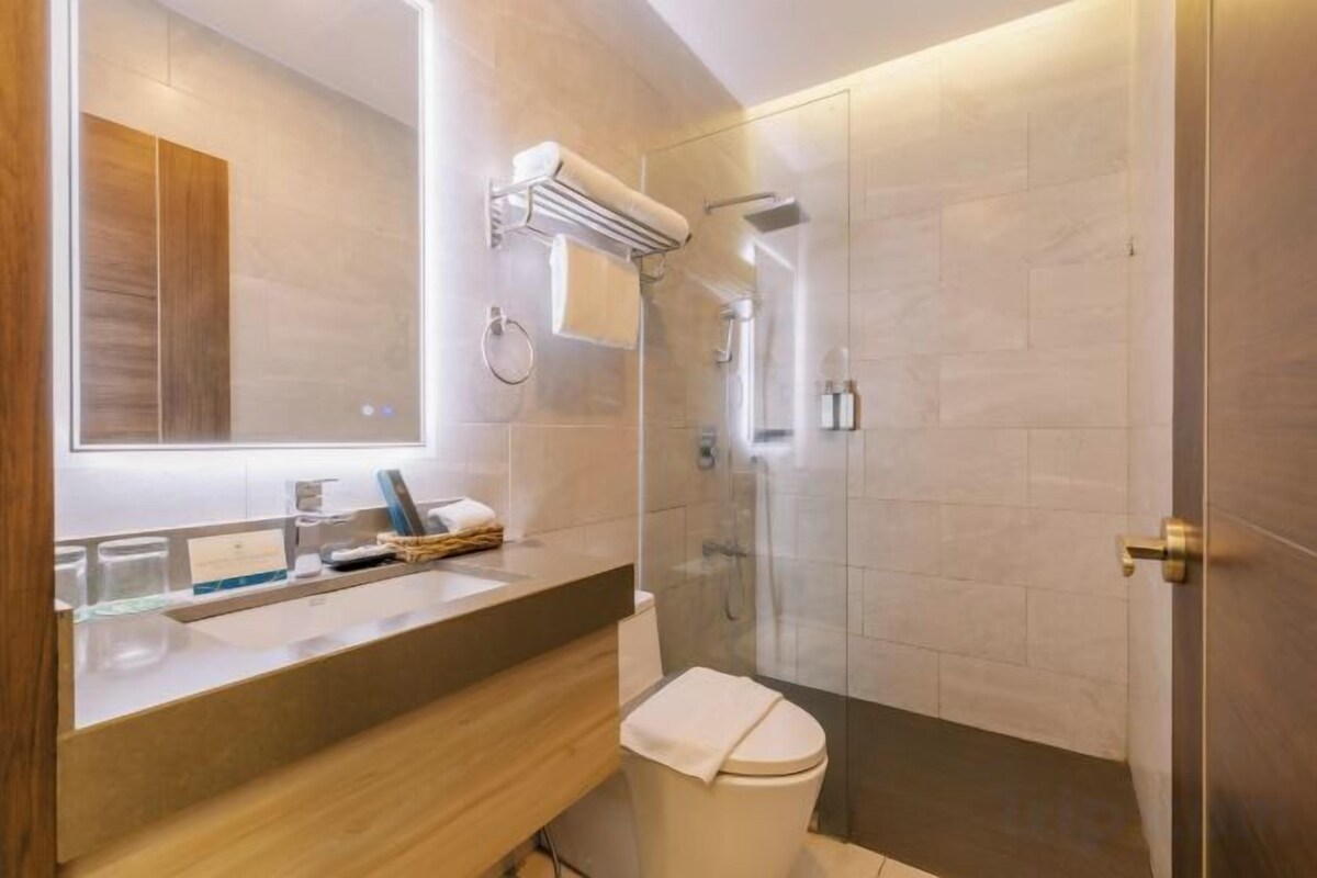 Un bagno moderno con uno specchio grande, un lavabo, un water e una zona doccia.