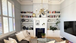 Un salon comprenant un canapé, une table basse en verre, une cheminée, des étagères et un téléviseur.