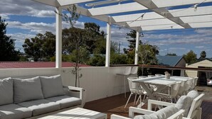 Une terrasse extérieure meublée de mobilier blanc, comprenant un canapé, des fauteuils et une table.