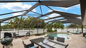 Eine Terrasse im Freien mit Pool, Grill und Sitzbereichen.