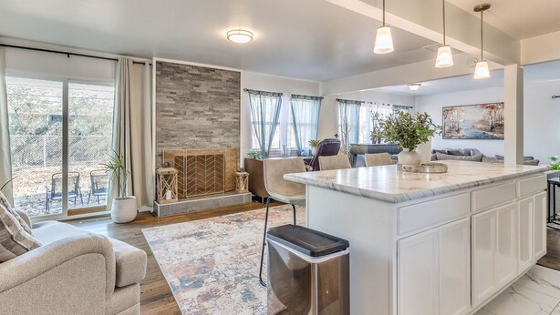 A modern kitchen with a large island, a dining area with a table and chairs, and a living room with a sofa and a fireplace. - Stylish home close to golf court & a casino (Tulsa)