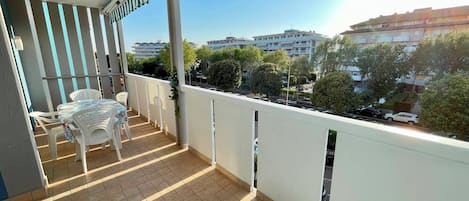 A balcony with a tiled floor, white railing, and a table with chairs.