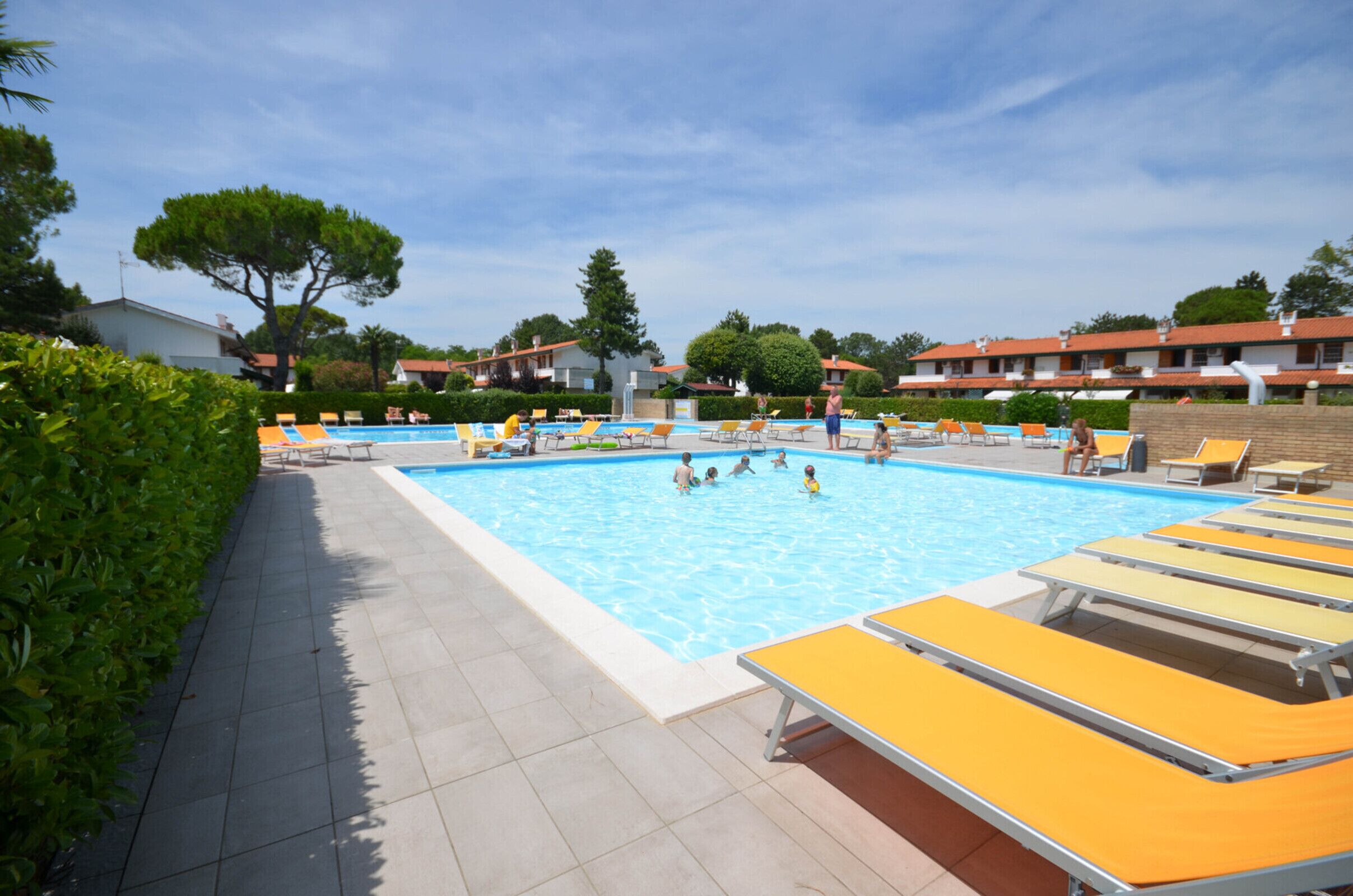 A swimming pool with lounge chairs and a tiled deck.