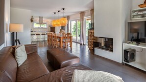 A modern living room with a brown leather sofa, a fireplace, and a dining area with a wooden table and chairs. - Beautiful apartment for 6 people with WIFI, TV, terrace and pets allowed (Frauenstein)
