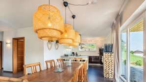 A modern kitchen with a dining area, featuring a wooden table and chairs, a large window with a view, and a stack of firewood. - Beautiful apartment for 6 people with WIFI, TV, terrace and pets allowed (Frauenstein)