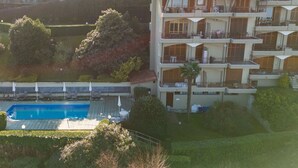 Un edificio de varios pisos con balcones, piscina y zonas verdes alrededor.